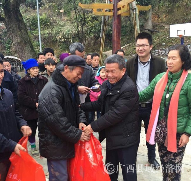 融水县政协副主席何来源（右二）给贫困户发放捐赠物品mmexport1484833795353